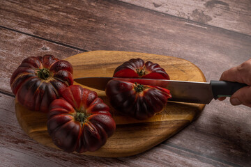 woman's hand with knife cutting tomatoes on a board - obrazy, fototapety, plakaty
