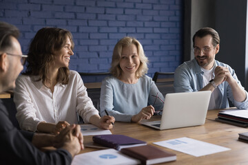 Positive senior mentor woman training employees, interns, laughing with staff, joking at conference...