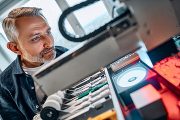 Portrait of a man looking at a machine that creates microchipsDevelopment of microchips, technology.