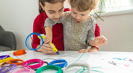 Child 3D drawings with a pen on the table. Selective focus.