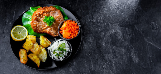 Pork cutlet coated with breadcrumbs with potatoes and salads