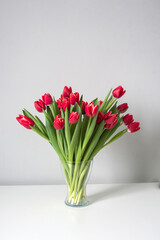Red kung fu tulips stand in a glass vase on the table. Bouquet of flowers