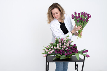 A sweet girl collected a bouquet of different varieties of tulips. Stands on a white background