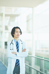 総合病院の廊下で腕組みをする若い男性医師