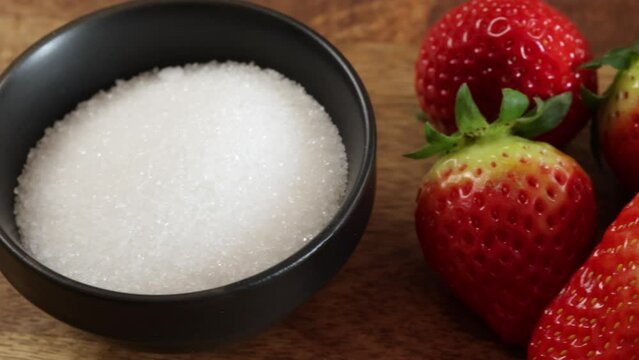 gros plan sur une fraise tremp&eacute;e dans un ramequin de sucre