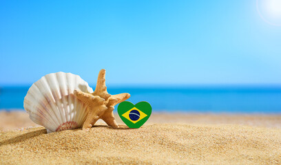 Beautiful beach in Brazil. Brazilian flag in the shape of a heart and seashells on a sandy beach