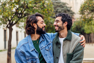 Fototapeta premium young couple of gay men looking into each other's eyes tenderly, concept of urban lifestyle and love between people of the same sex, copy space for text