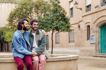 young couple of gay men smiling happy holding hands tenderly, concept of urban lifestyle and love between people of the same sex, copy space for text