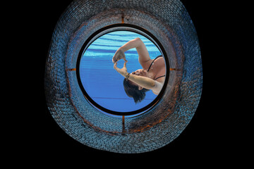 Woman Making a Heart Shape with Her Hands in the Ship Porthole in Underwater in Swimming Pool in a Sunny Day in Switzerland.