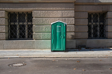 green portable chemical toilet on a sidewalk