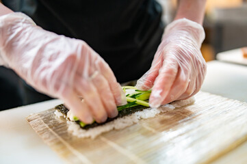 Obraz premium professional chef's hands making sushi roll in a restaurant kitchen