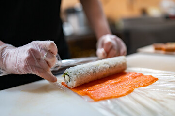 professional chef's hands making sushi roll in a restaurant kitchen
