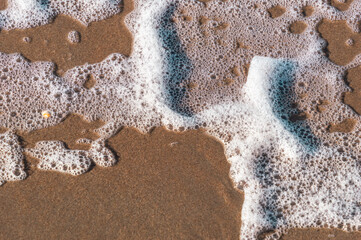 Sea foam patterns on the beach on a sunny day