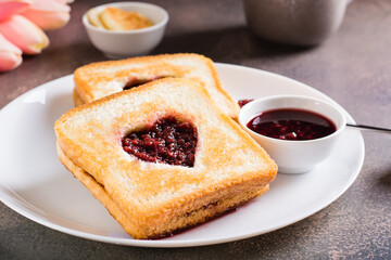 Heart shaped toast with raspberry jam on a plate. Food for lovers.