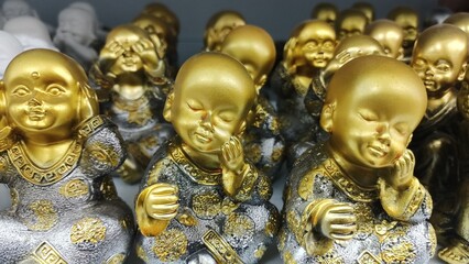 Golden statues of a boy who does not hear, does not see and touches his face with his hands