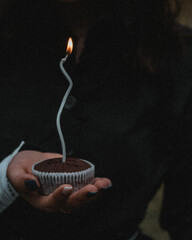 Hand holding a birthday cake with a candle