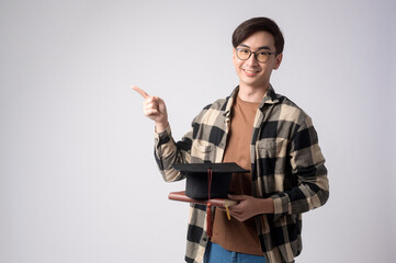 Young smiling man holding graduation hat, education and university concept.