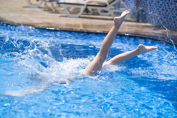 the girl dives into the pool, only her legs stick out of the water