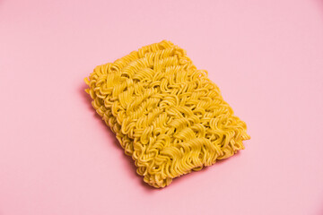 Flatlay, raw instant noodles on pink paper background with copy space