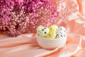 Easter composition on a background of pink satin quail eggs in a white ceramic bowl.  On the back...