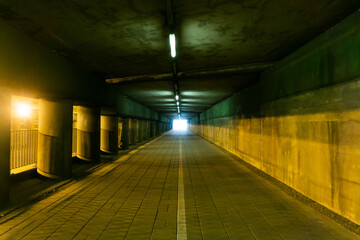 Horror tunnel background. Dark pavement tunnel with bright light at the end. Scary walkway under...