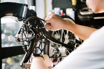 Fototapeta premium Technician makes adjustments to Crankset and repairing the gearshift on a folding bicycle working in workshop , Bicycle Repair and maintenance concept