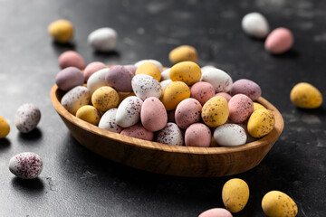 Easter mini eggs, chocolate candy in wooden bowl