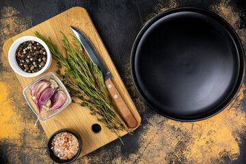 Empty black plate and cutting board with spices on meat table, top view, food photo or menu mockup