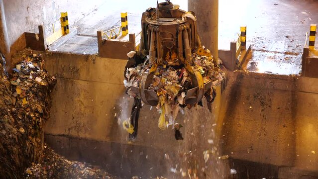 A huge claw grabs a portion of garbage for delivery to the oven. Unsorted garbage is collected by a special crane claw for incineration at the factory. Recycling of garbage. Fuel for thermal power.