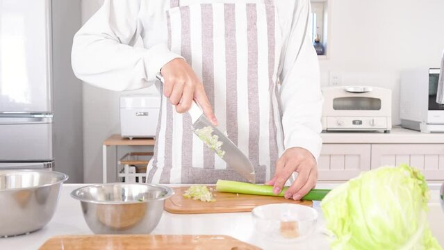 キッチンでネギを切る40代の男性