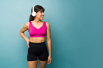 Fototapeta na wymiar Fitness young woman with headphones showing her arm muscles