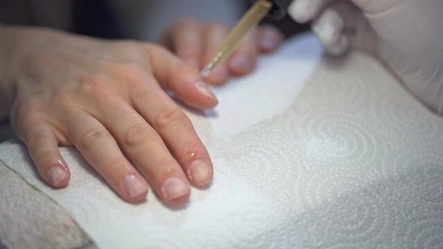 Manicurist applies cuticle oil to her client