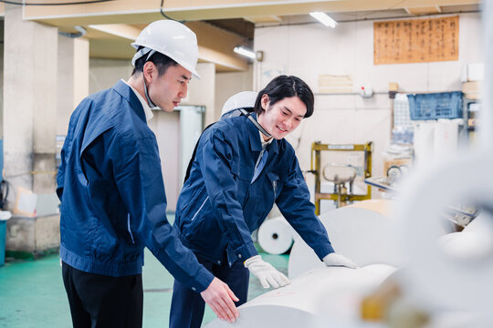 印刷工場でロール紙の確認をする作業員