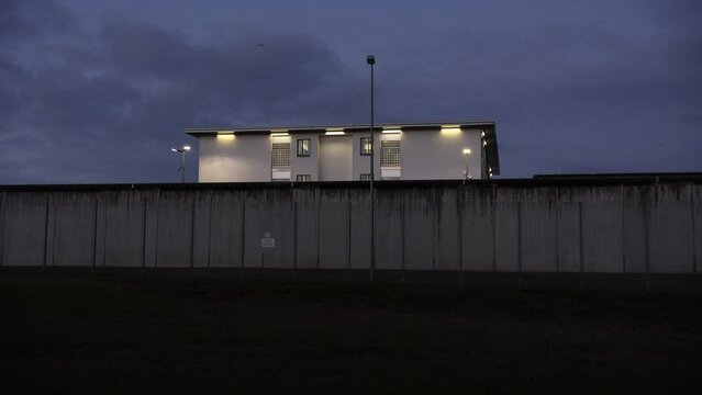 A prison with high concrete walls and barbed wire.

