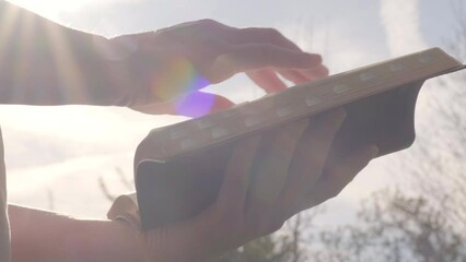 Stock reading bible page turning slow motion outside sunny day