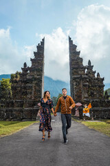 Obraz premium Young Couple Running Through Handara Gate In Bali, Indonesia