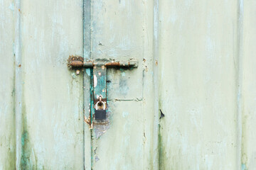 Grunge garage door. Black padlock texture. Metal entrance. Old peeling paint gate. Aged car garage iron door. Green color paint.