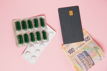 Flatlay, pills, money and bank card on a pink background. Concept of ordering medicine online