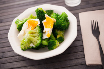 boiled broccoli inflorescences with boiled egg in plate