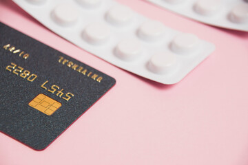 Credit card and pills in white blisters on a pink background. Concept of ordering medicine online