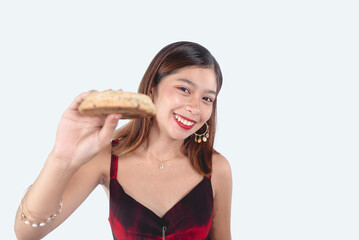 A beautiful young woman showing a large piece of chocolate chip cookie. Assuming filling her sweet cravings. Wearing a red dress. Isolate in a white background.