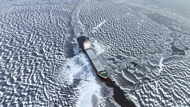 A big red ship frozen in the endless sea of ice. Aerial View of dead frozen harbour Extreme cold weather. Nature landscape famous for being heavily affected by global warming and Climate Change
