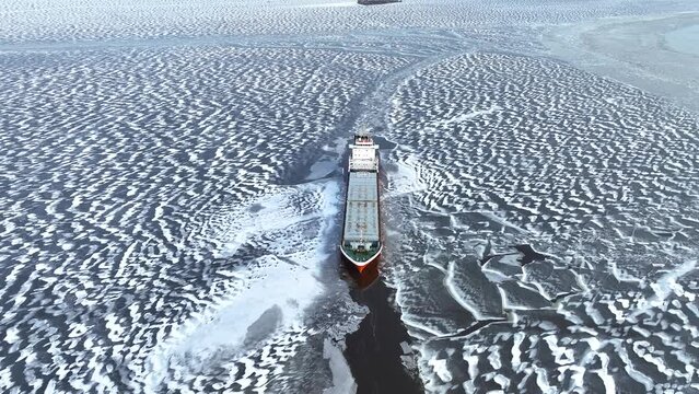 A big red ship frozen in the endless sea of ice. Aerial View of dead frozen harbour Extreme cold weather. Nature landscape famous for being heavily affected by global warming and Climate Change