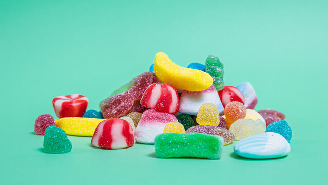 Gominolas multicolores amontonadas en el centro sobre fondo verde 