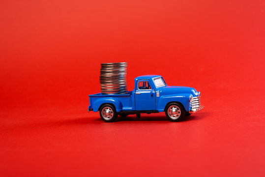 toy vintage car carrying coins on red background