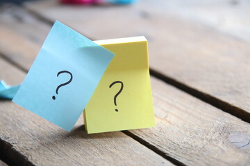 Question marks on cards on a wooden background.