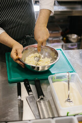 Close up. A male cook prepares pancake batter in a metal bowl in the kitchen of a restaurant.