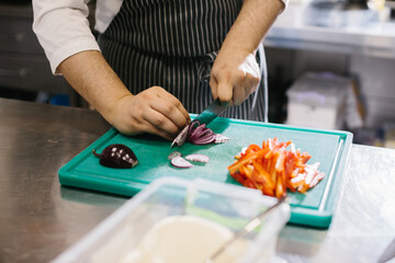 Fototapeta premium Close up, male chef cuts vegetables in restaurant.