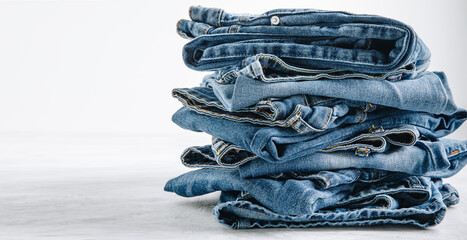 Jeans. Blue jeans trousers stack on light stone background