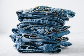 Jeans. Blue jeans trousers stack on light stone background